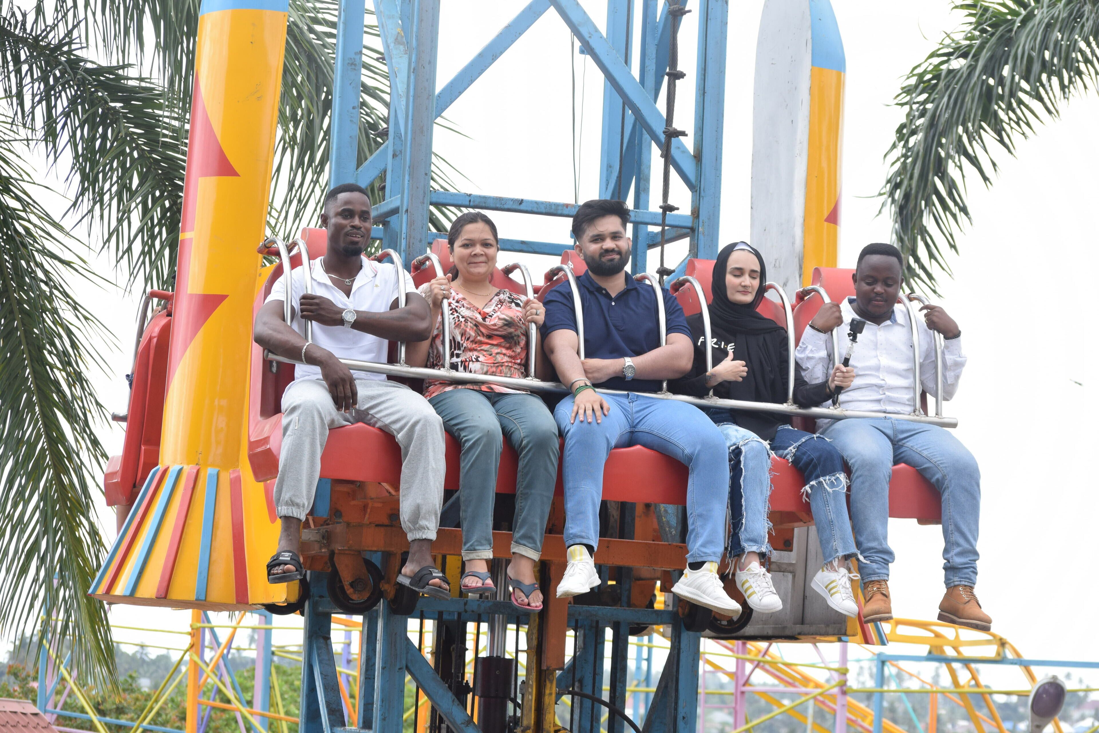 Un grupo de personas sentadas en una atracción de feria colorida.
