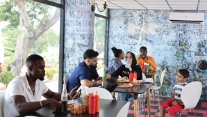 Un restaurant avec un mur couvert de graffitis, des tables, des chaises et des clients qui déjeunent ou dînent.
