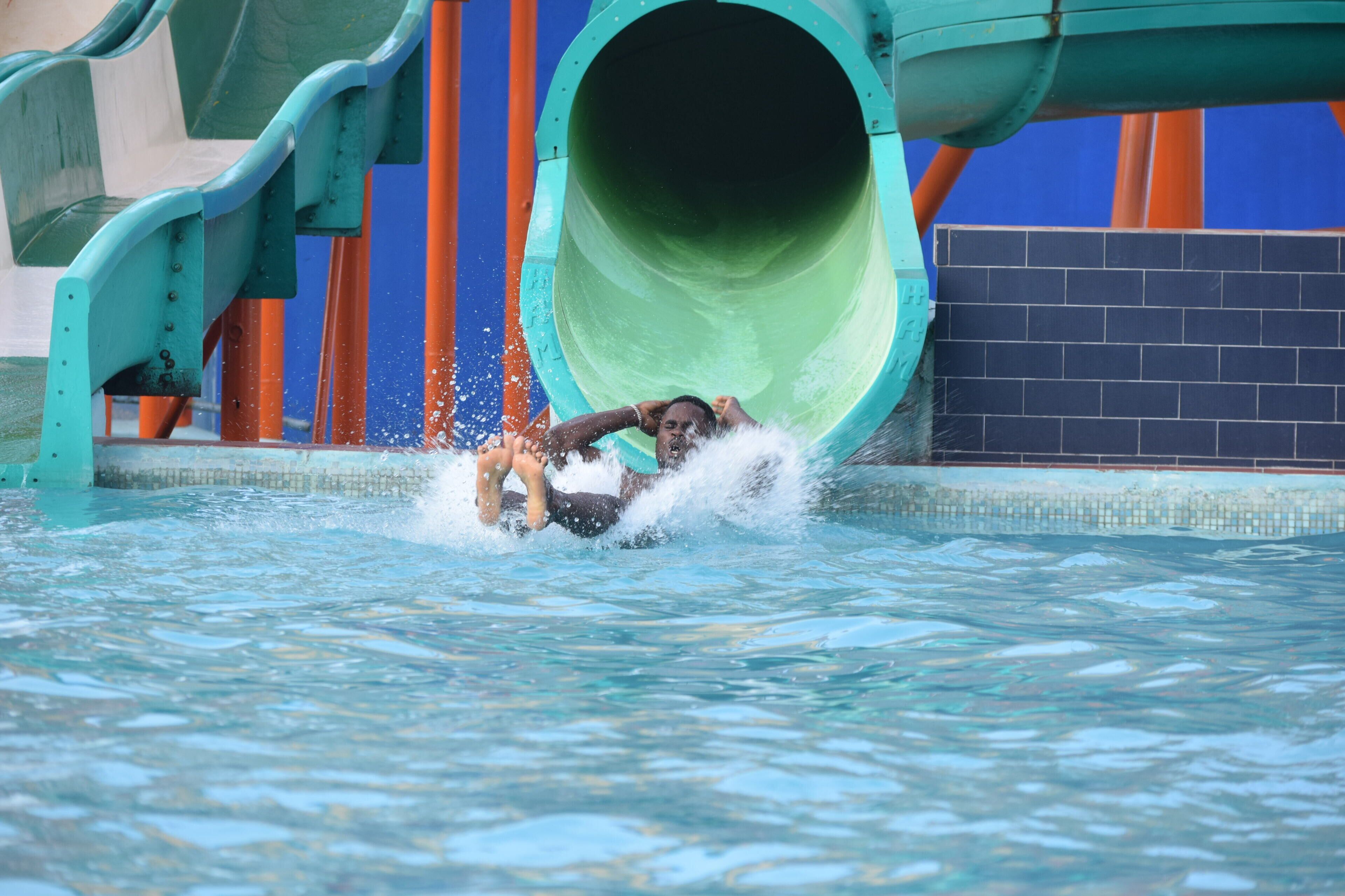 A person sliding down a water slide into a pool.