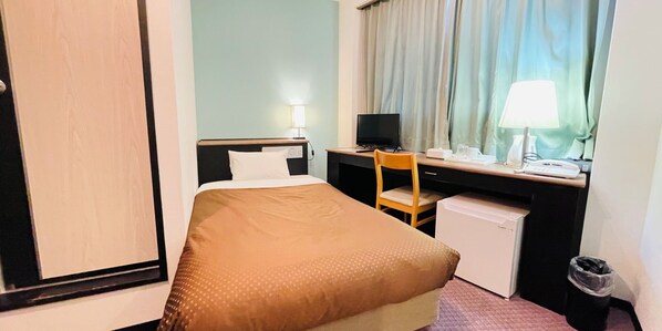 A hotel room with a bed, desk, chair, and a small refrigerator. - BUSINESS HOTEL KUDAMATSU (Kudamatsu)