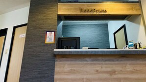 A reception desk with a wooden counter and a sign above it that reads "Reception". There is a computer monitor on the desk, and a sign on the wall to the left that says "Staff only". - BUSINESS HOTEL KUDAMATSU (Kudamatsu)