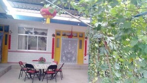 A building with a dining area featuring a round table and chairs, a window, and a door with decorative elements. - Xinyuan Hostel (Jingtai)