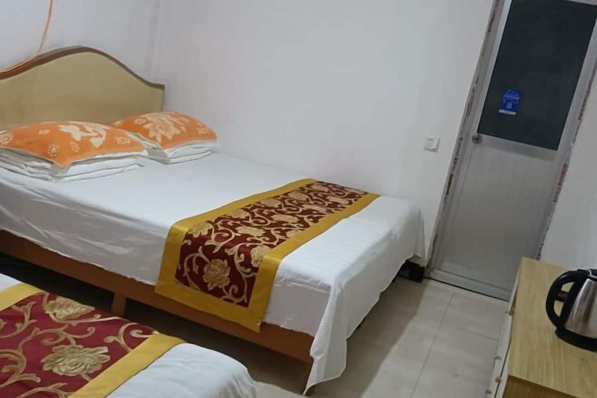 A single bed with a white mattress and a red and gold bedspread.