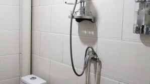 A bathroom with white tiled walls, a shower with a handheld showerhead, and a small trash bin. - Xinyuan Hostel (Jingtai)