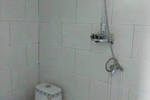 A bathroom with white tiled walls, a toilet, and a shower with a handheld showerhead and a wall-mounted faucet. - Xinyuan Hostel (Jingtai)