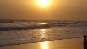 Une scène de plage au coucher du soleil sur l’océan, avec le texte « Cox’s Bazaar » visible.