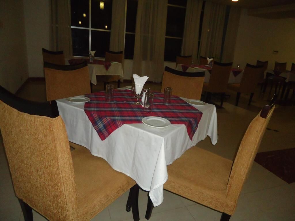A dining area with a table set for two, featuring a plaid tablecloth and white table settings.