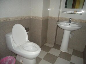 Une salle de bain avec des toilettes et un lavabo, des carreaux de sol à motifs géométriques et un miroir au-dessus du lavabo.