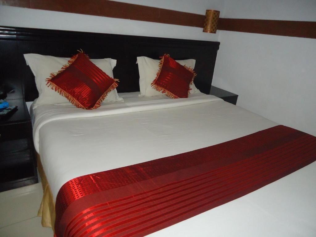 A bed with a white and red bedspread, two pillows with red and white patterns, and a wooden headboard.