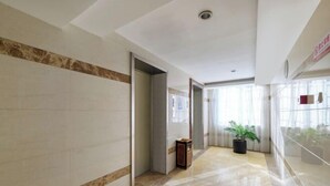 A hallway with a marble floor, a door, and a potted plant. - Yiting Business Hotel (Quanzhou)