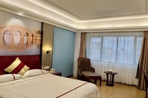 A hotel room with a large bed, a chair, a small table, a painting of a bridge, and a window with curtains. - Yiting Business Hotel (Quanzhou)