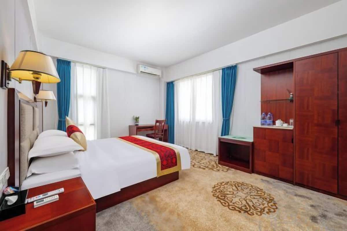 Une chambre d’hôtel comprenant un lit, une table de chevet, une lampe, une armoire et un sol recouvert de moquette.