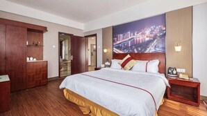 A hotel room with a large bed, wooden wardrobe, a nightstand, and a cityscape view. - Yiting Business Hotel (Quanzhou)