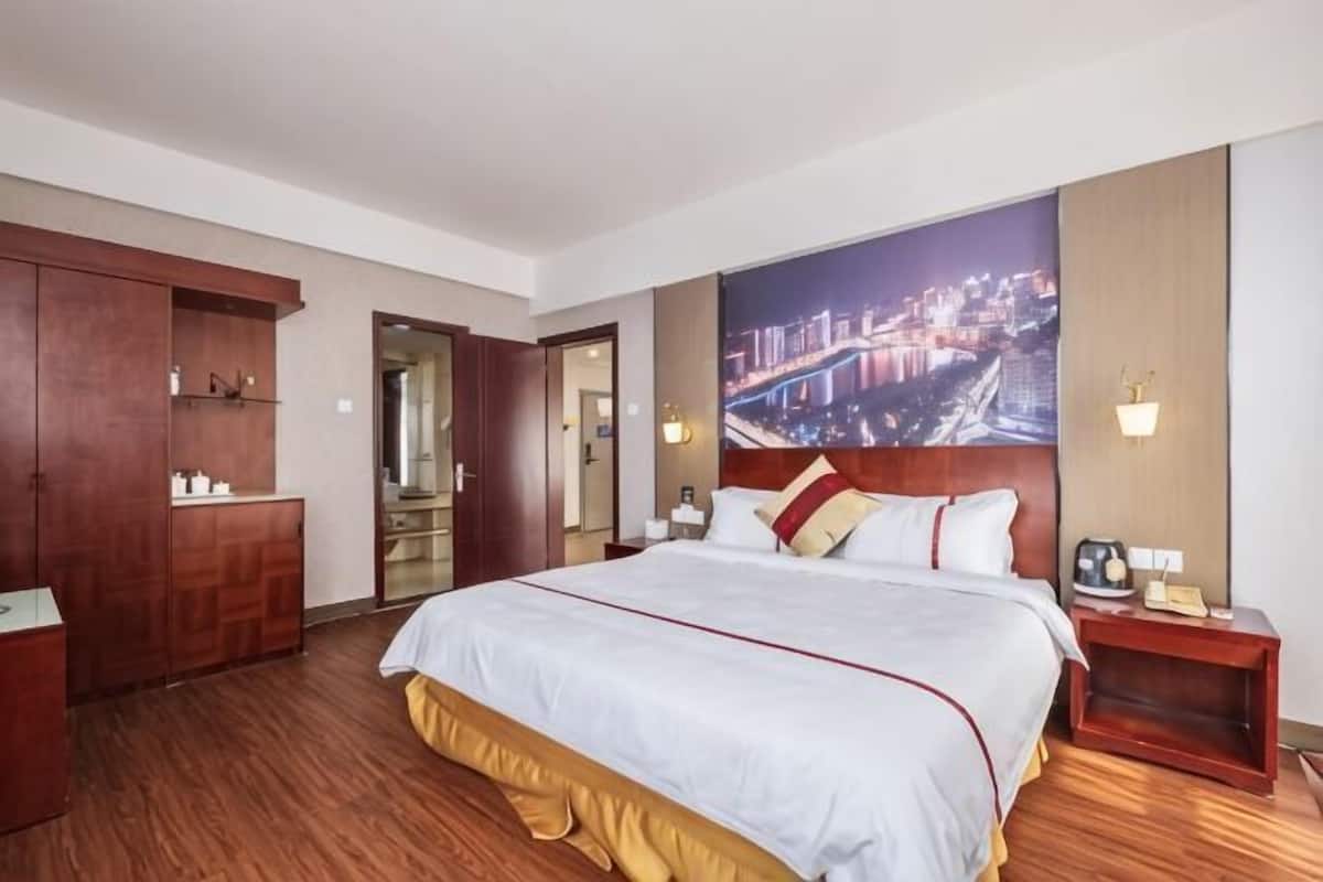 Une chambre d’hôtel avec un grand lit, une armoire en bois, une table de chevet et une vue sur la ville.
