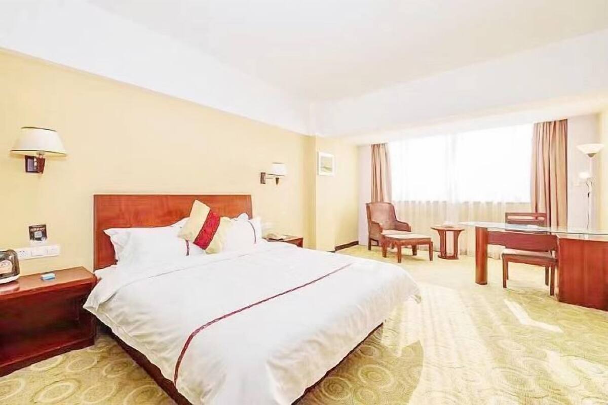 Une chambre d’hôtel avec un grand lit, un bureau, une chaise et une petite table.