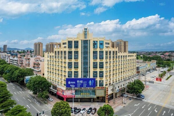 A multi-story hotel with a central atrium, surrounded by a parking lot and a street. - Yiting Business Hotel (Quanzhou)