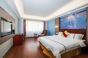 A hotel room with a large bed, a flat-screen TV, a small table, a chair, and a painting on the wall. - Yiting Business Hotel (Quanzhou)
