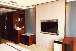 A hotel room with a bed, a TV mounted on the wall, a wardrobe, and a small table with a green coaster. - Yiting Business Hotel (Quanzhou)