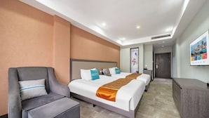 A hotel room with a bed, a grey armchair, a desk, and a door leading to another room. - Nanxun Liwei Boutique Hotel (Huzhou)