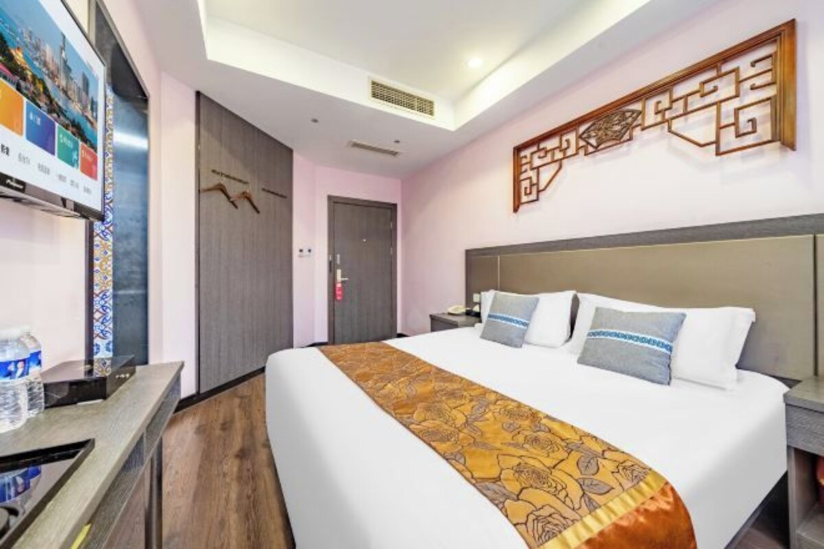 Una habitación de hotel con una cama grande, un escritorio con computadora y un televisor montado en la pared.