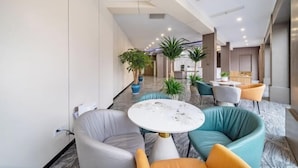 A modern hotel lobby with a curved seating area, a marble table, and potted plants. - Nanxun Liwei Boutique Hotel (Huzhou)