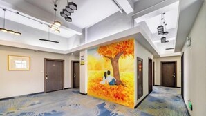 A spacious hotel lobby with a large mural of a tree and two people sitting beneath it. - Nanxun Liwei Boutique Hotel (Huzhou)