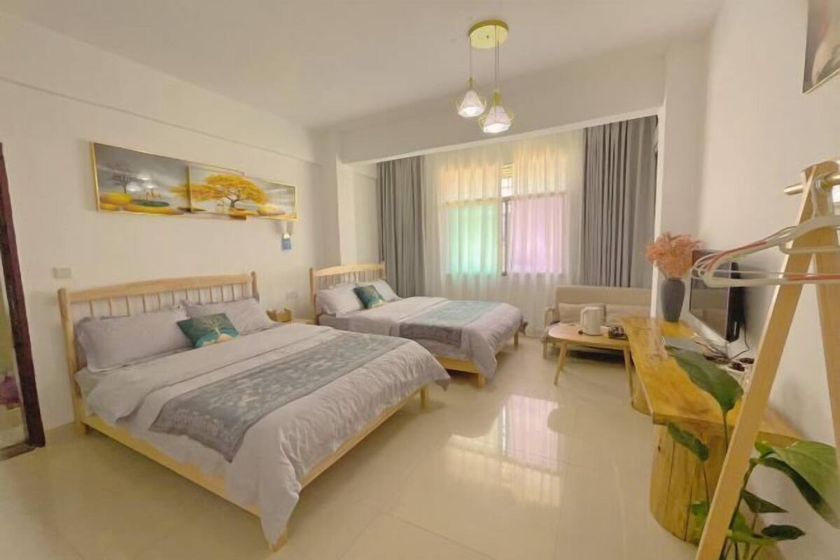 A bedroom with two beds, a TV, a desk, and a painting on the wall.