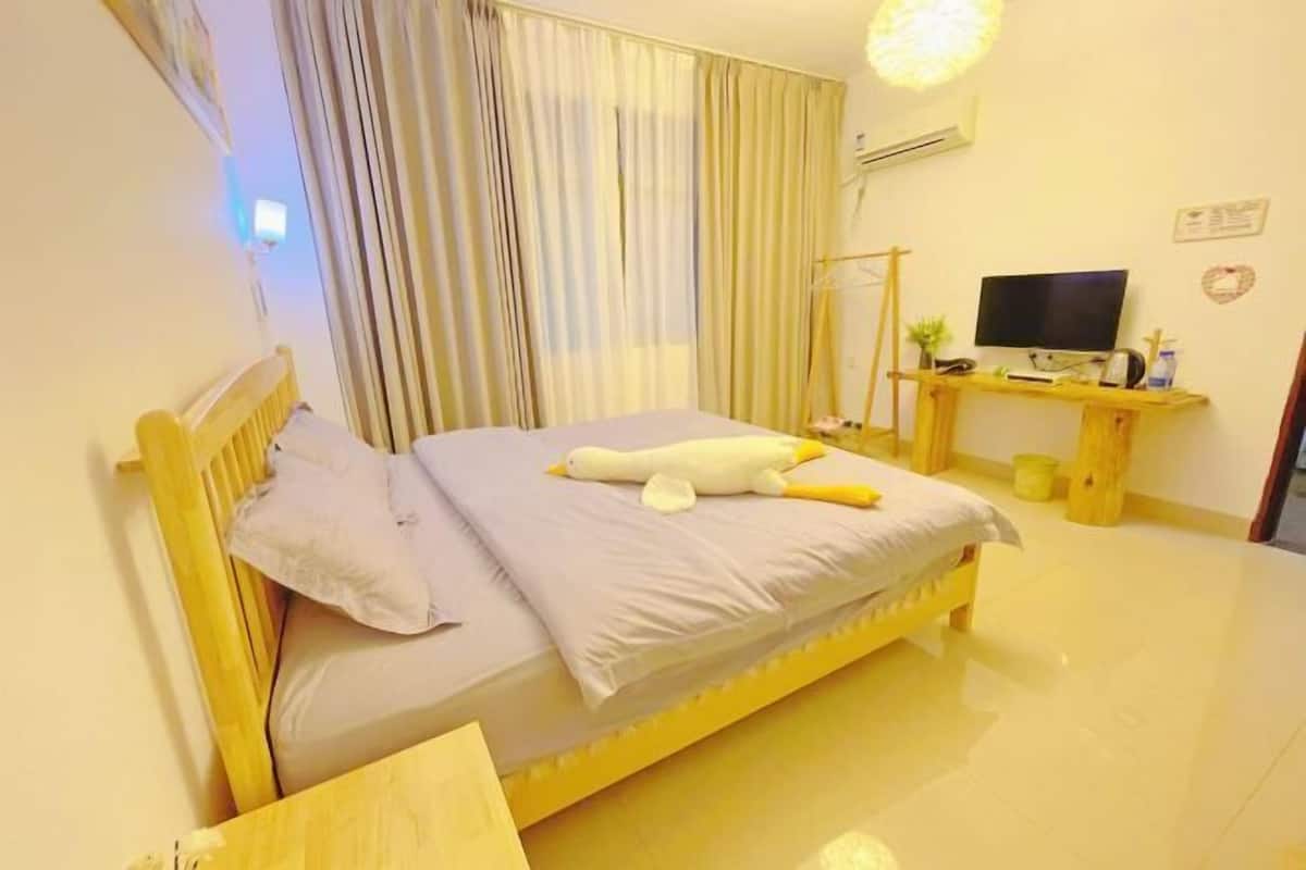 A bedroom with a bed, curtains, a television, and a desk with a computer.