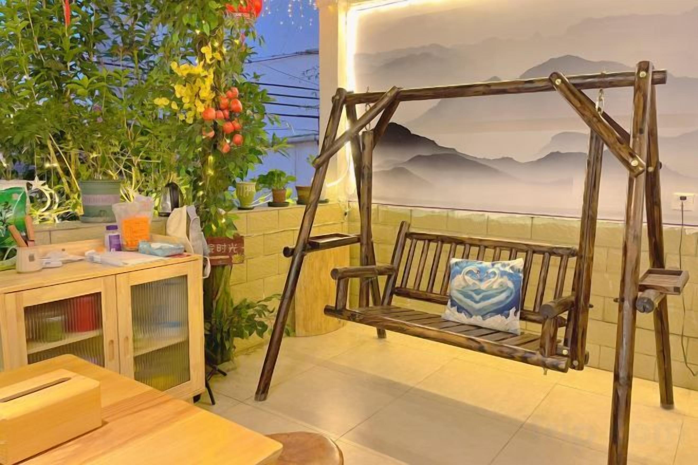 A wooden swing with cushions, a wooden table, and a cabinet with items on it.