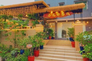 A hotel entrance with a staircase, potted plants, and a thatched roof structure. - Alley See You Inn (Danxia Mountain Scenic Area) (Renhua)