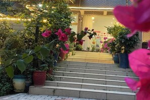 A set of outdoor steps leading to a building entrance, surrounded by potted plants and flowers. - Alley See You Inn (Danxia Mountain Scenic Area) (Renhua)