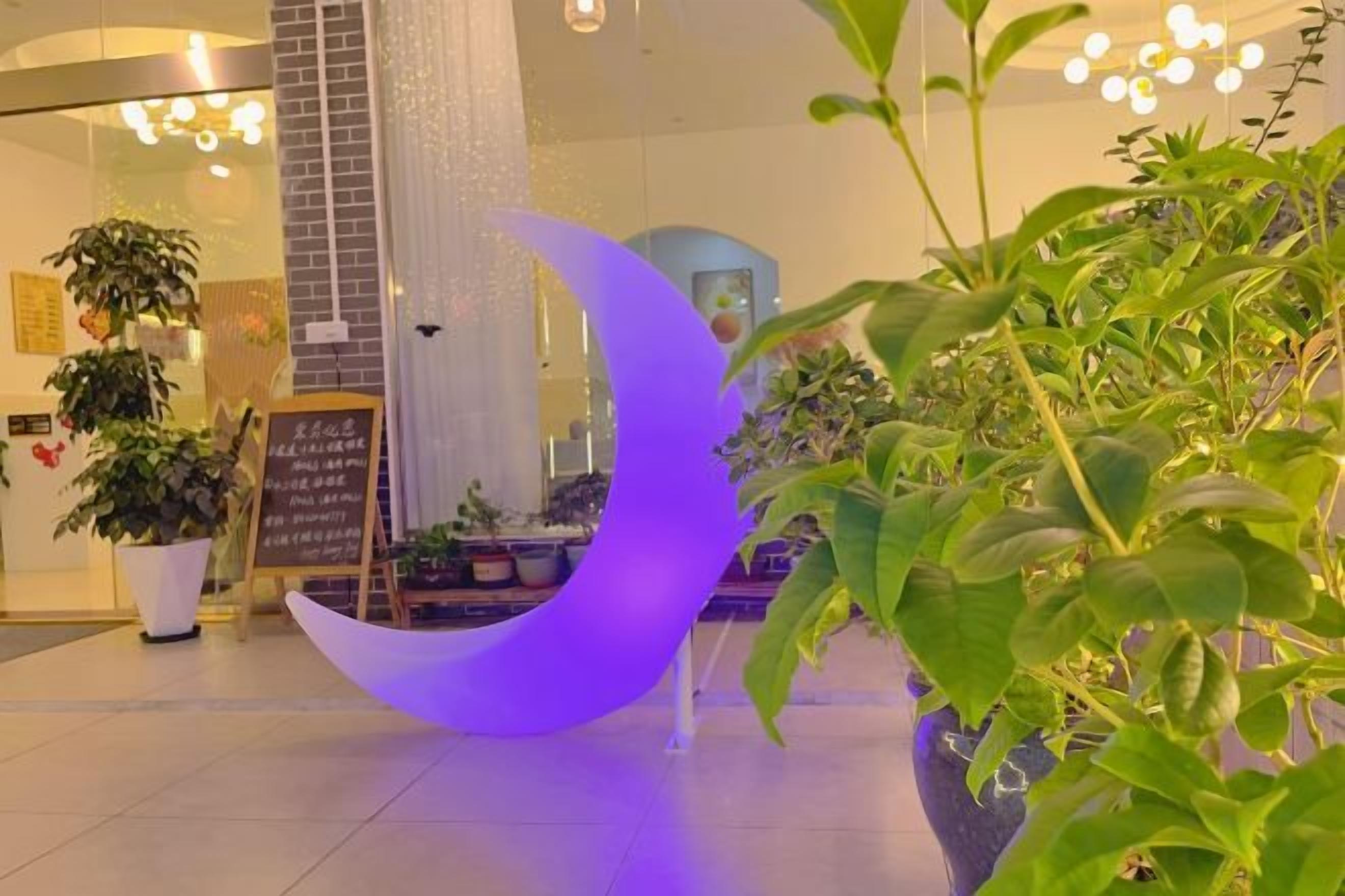 A modern interior with a crescent-shaped light fixture, potted plants, and a chalkboard menu.