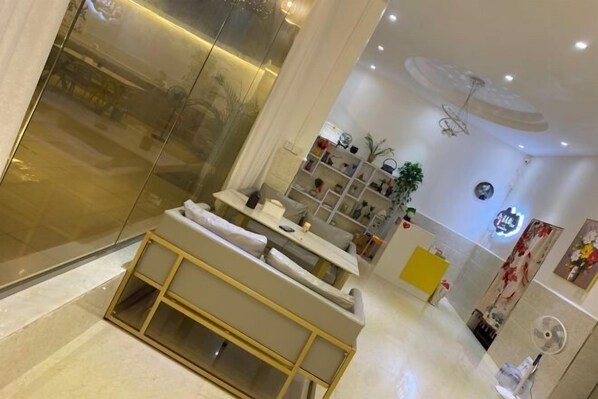 A modern interior with a seating area, a reception desk, and a wall-mounted shelf with decorative items. - Alley See You Inn (Danxia Mountain Scenic Area) (Renhua)