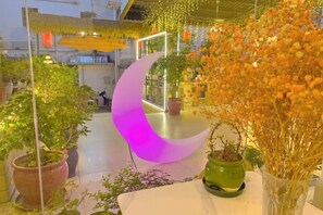 A rooftop garden with potted plants, a crescent-shaped light fixture, and hanging decorations. - Alley See You Inn (Danxia Mountain Scenic Area) (Renhua)