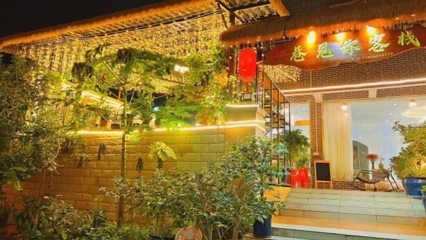 Un edifici amb teulada de palla, una escala que condueix a l'entrada i plantes en testos al voltant de l'exterior.