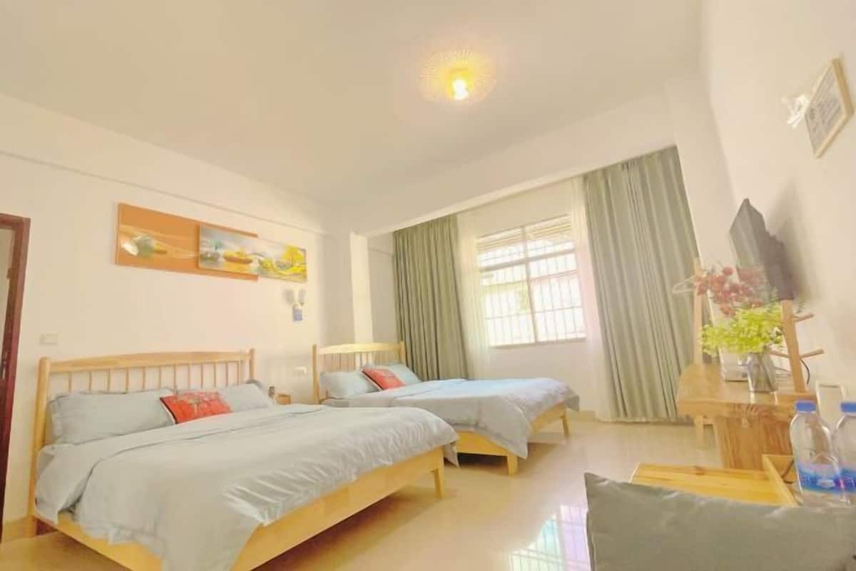 A hotel room with two wooden beds, a desk with a chair, a television, and a window with curtains.