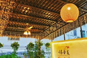 A room with a ceiling fan, hanging lights, and a large yellow sign with Chinese characters. - Alley See You Inn (Danxia Mountain Scenic Area) (Renhua)