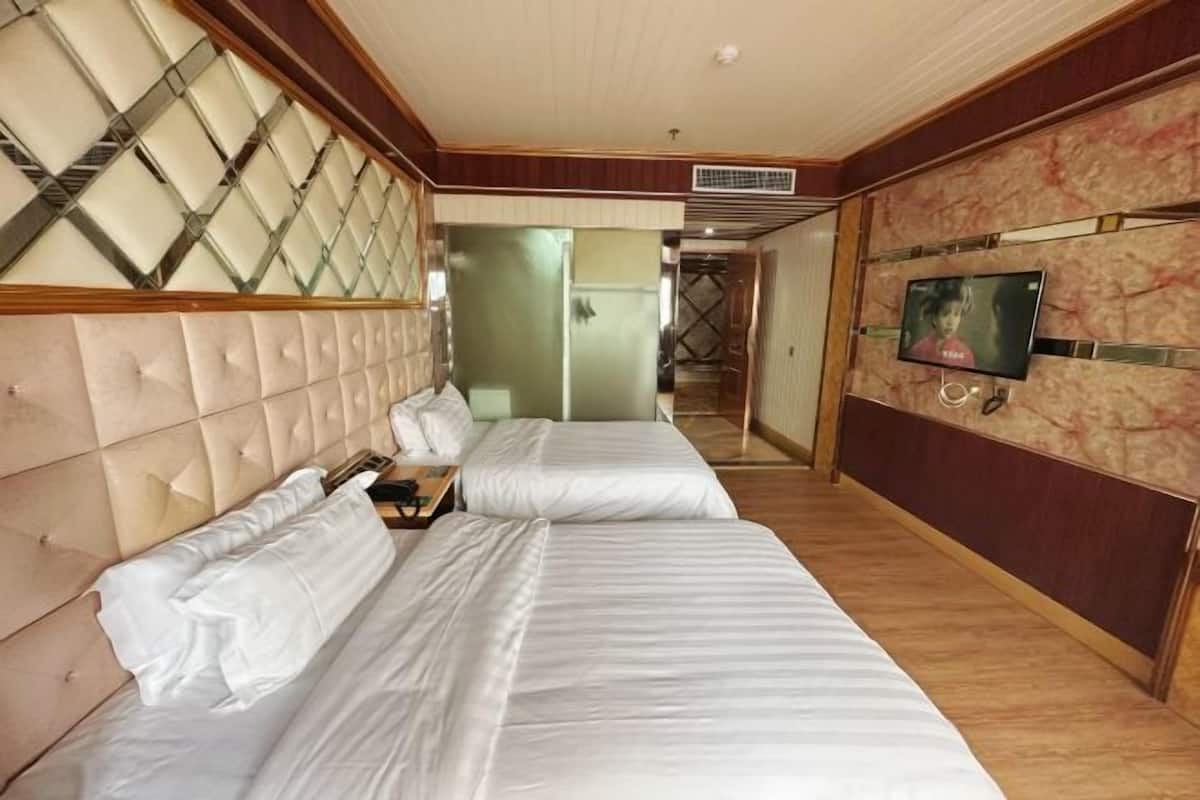 A hotel room with two beds, a television, and a decorative wall.