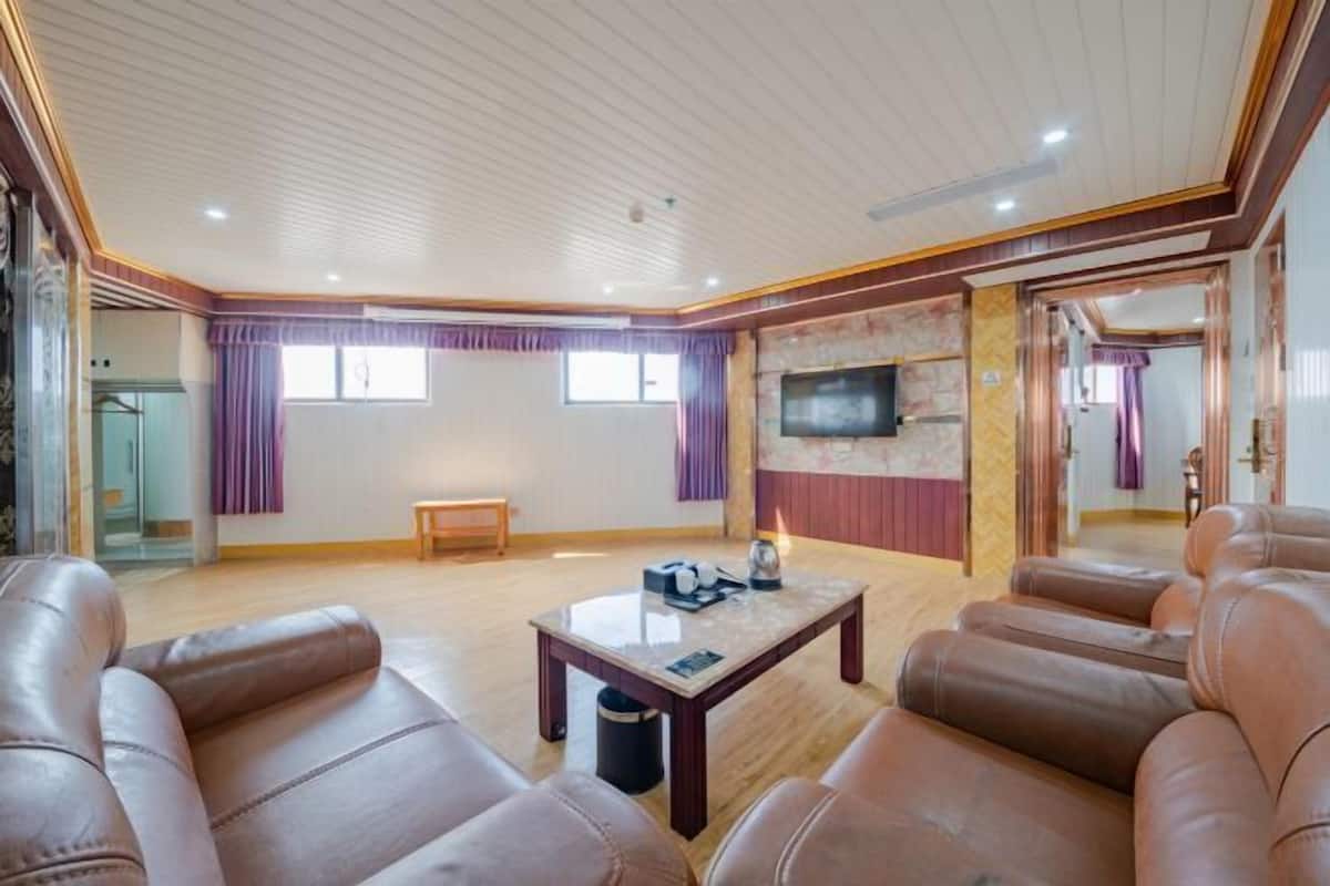A spacious living room with leather sofas, a wooden coffee table, a flat-screen TV, and a stone accent wall.