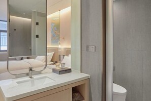 Un baño moderno con un espejo grande, un lavabo blanco y un inodoro.