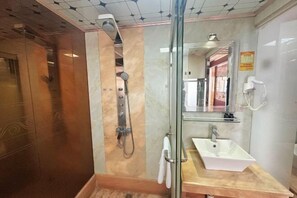 A bathroom with a glass-enclosed shower, a sink, a mirror, and a hairdryer on the wall. - Zhongmao Yishang Hotel (Jiexi)