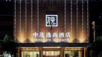 Exterior del hotel Zhongmaoyi Shang, con señalización iluminada y fachada moderna.