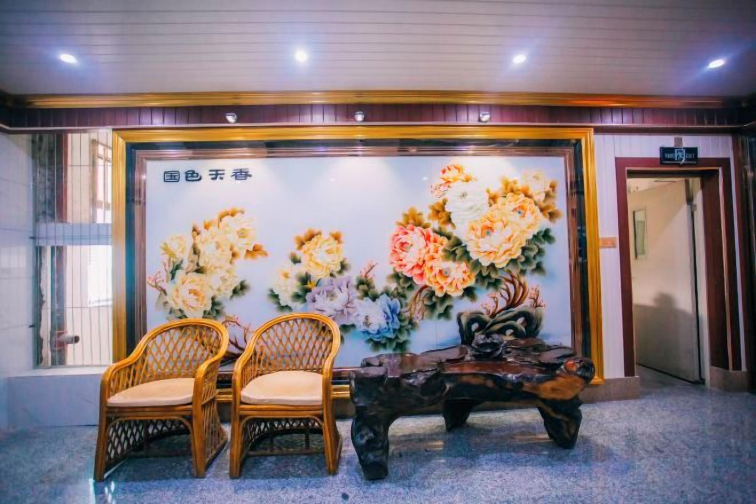 A reception area with a floral wall mural, two wicker chairs, and a wooden bench.