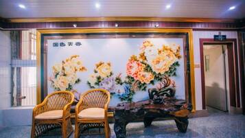 A reception area with a floral wall mural, two wicker chairs, and a wooden bench.