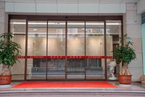 A hotel entrance with a glass door, a red carpet, and potted plants. - Zhongmao Yishang Hotel (Jiexi)