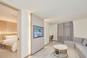 Una habitación de hotel moderna con una cama, una mesita, un sofá y una pantalla digital en la pared.