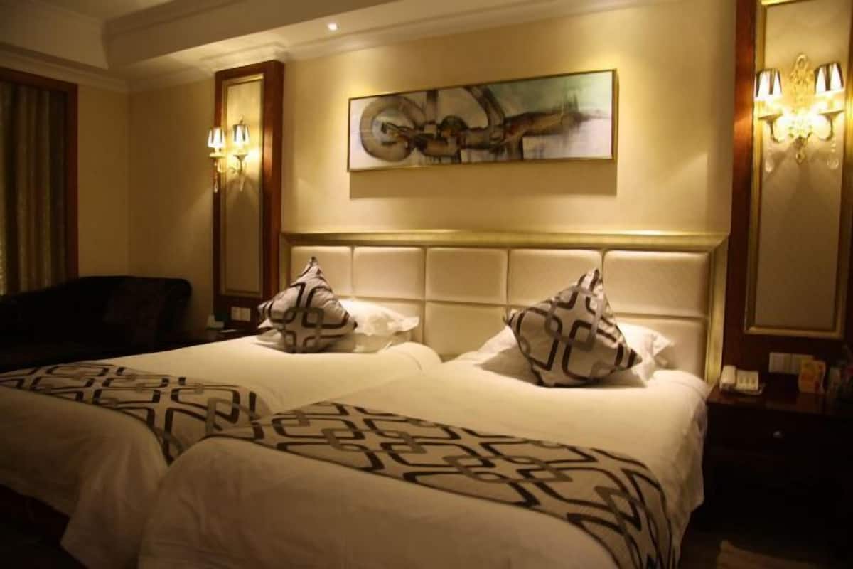 Habitación de hotel con dos camas, un cuadro abstracto de gran tamaño y apliques de pared.