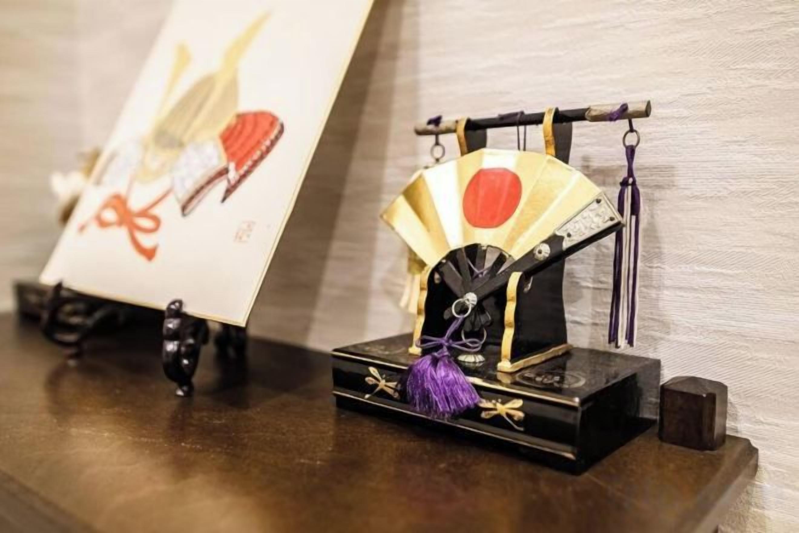 A display of traditional Japanese items, including a fan and a small model of a fan on a shelf.