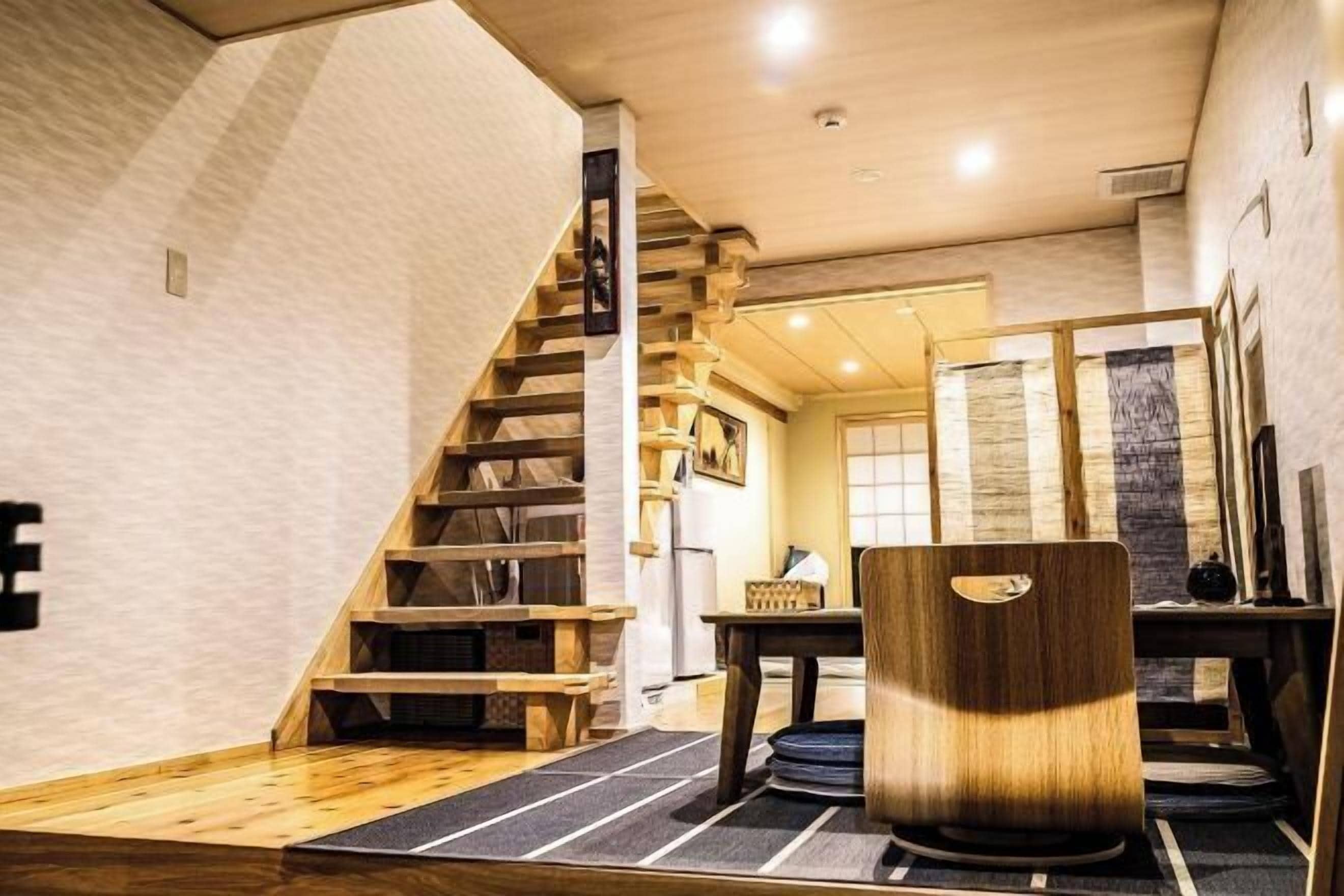 A modern interior with a wooden staircase, a dining area, and a view of the outside.