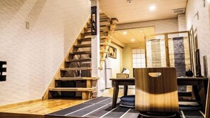 A modern interior with a wooden staircase, a dining area, and a view of the outside.